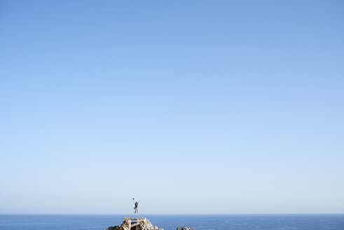 Spanien, glückliche Frau springt in die Luft vor blauem Himmel - IGGF00152