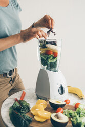 Woman filling fruit and vegetable into blender - IPF00413