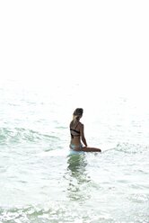 Frau sitzt auf einem Surfbrett im Ozean - ECPF00053
