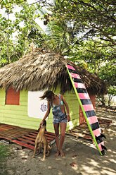 Frau mit Hund und Surfbrett an der Küste - ECPF00078