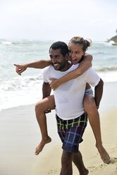 Mann nimmt seine Freundin am Strand huckepack - ECPF00084