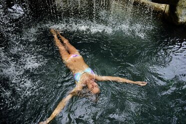 Junge Frau schwimmt im Wasser in einem Pool mit Wasserfall - ECPF00087