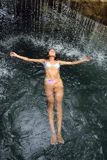 Junge Frau schwimmt im Wasser in einem Pool mit Wasserfall - ECPF00088