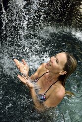 Happy woman in natural pool with waterfall - ECPF00093