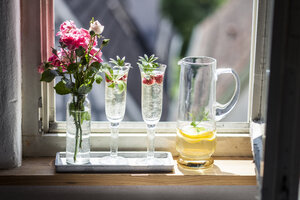 Zwei Champagnergläser mit Maiwein und Himbeeren auf der Fensterbank - SBDF03301