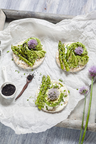 Reisküchlein mit Frischkäse, Avocado und Spargel, garniert mit Schwarzkümmel und Schnittlauchblüte, lizenzfreies Stockfoto