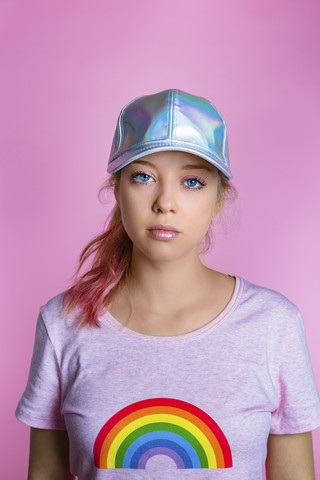Porträt einer stilvollen jungen Frau mit Basecap vor einem rosa Hintergrund, lizenzfreies Stockfoto