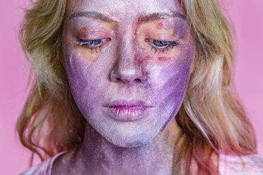 Porträt einer jungen Frau mit metallischem Schimmer im Gesicht vor einem rosa Hintergrund - MGIF00115