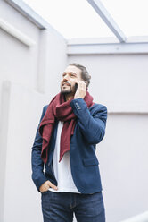 Portrait of smiling businessman on the phone wearing scarf - JOSF01540