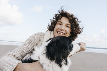 Glückliche Frau mit Hund am Strand - KNSF02539