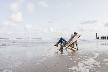Woman sitting on deckchair on the beach - KNSF02540