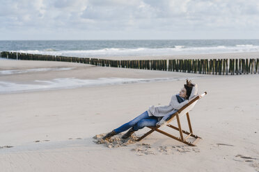 Frau sitzt auf einem Liegestuhl am Strand - KNSF02541