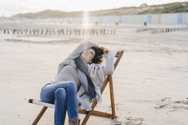 Woman sitting on deckchair on the beach - KNSF02542