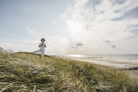 Frau übt Yoga in der Stranddüne, lizenzfreies Stockfoto