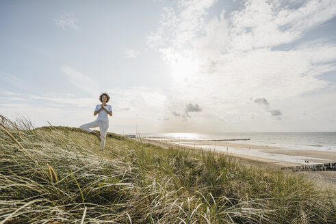 Woman practicing yoga in beach dune - KNSF02545