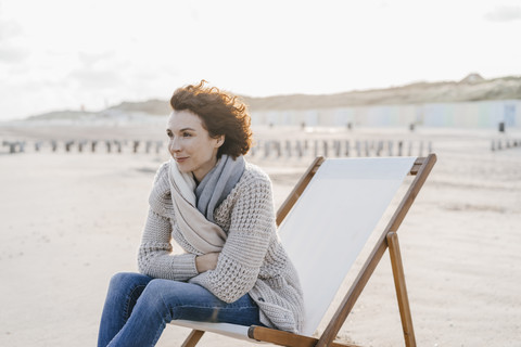 Frau sitzt auf einem Liegestuhl am Strand, lizenzfreies Stockfoto