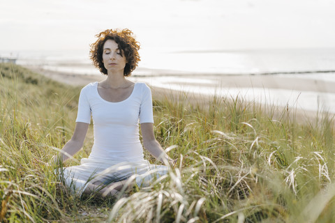 Woman practicing yoga in beach dune stock photo