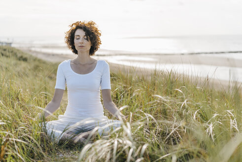 Woman practicing yoga in beach dune - KNSF02548