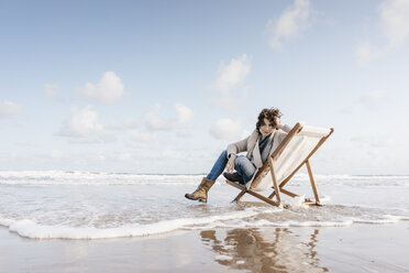 Woman sitting on deckchair on the beach - KNSF02550