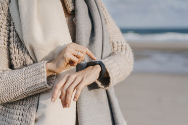 Frau am Strand überprüft ihre Smartwatch - KNSF02551