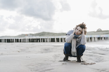 Frau hockt am Strand - KNSF02566