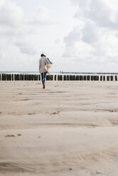 Frau geht am Strand spazieren - KNSF02569