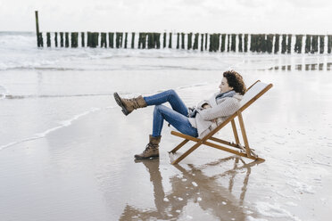 Woman sitting on deckchair on the beach - KNSF02571