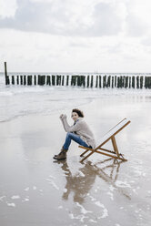 Woman sitting on deckchair on the beach - KNSF02573