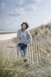 Frau steht in einer Stranddüne und spricht mit ihrem Handy - KNSF02577