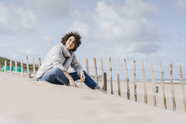 Frau sitzt am Strand - KNSF02580