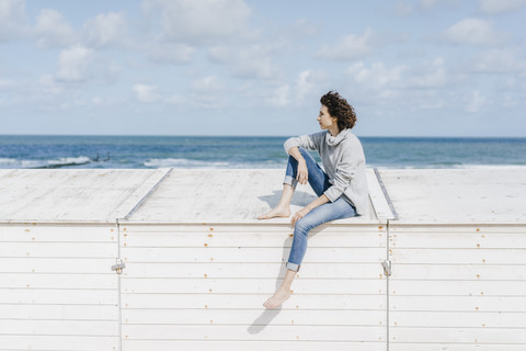 Woman sitting on wooden box on the beach stock photo