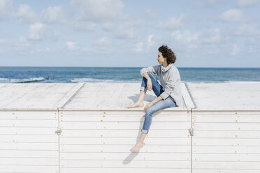 Woman sitting on wooden box on the beach - KNSF02584