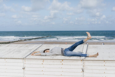 Woman lying on wooden box on the beach - KNSF02585