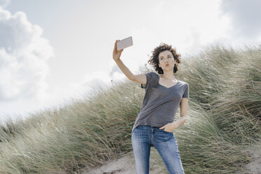 Frau steht in einer Stranddüne und macht ein Selfie - KNSF02588