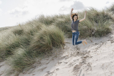 Happy woman jumping in beach dune - KNSF02589