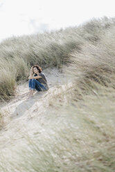 Woman sitting in beach dune - KNSF02590