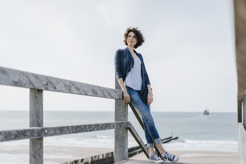 Frau steht auf der Strandpromenade am Strand, lizenzfreies Stockfoto