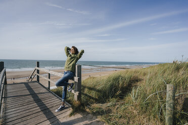 Woman standing on boardwalk at the beach - KNSF02602