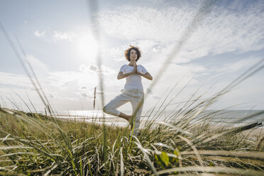 Woman practicing yoga in beach dune - KNSF02607