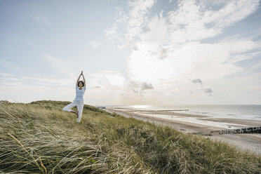 Woman practicing yoga in beach dune - KNSF02610