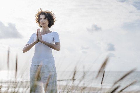 Frau übt Yoga in der Stranddüne, lizenzfreies Stockfoto