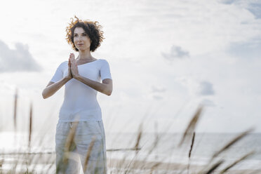 Woman practicing yoga in beach dune - KNSF02611