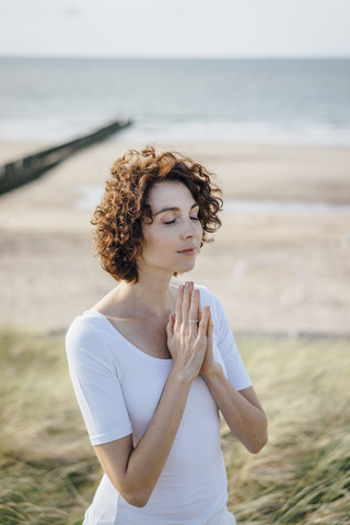 Woman practicing yoga in beach dune stock photo