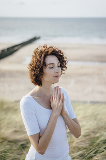 Woman practicing yoga in beach dune - KNSF02612