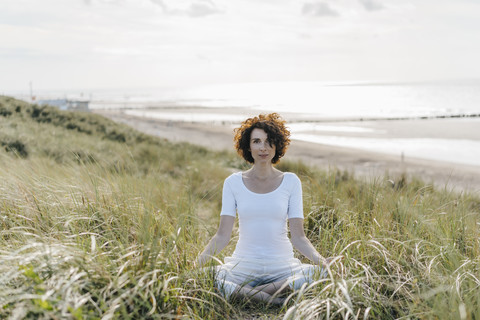Woman practicing yoga in beach dune stock photo