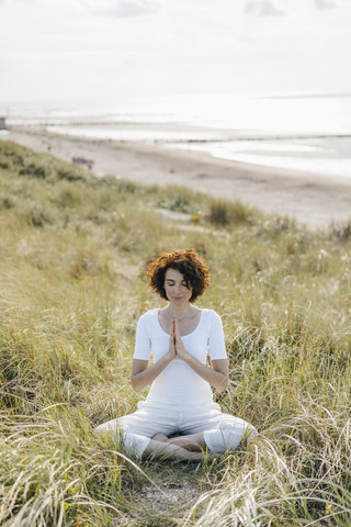 Frau übt Yoga in der Stranddüne, lizenzfreies Stockfoto