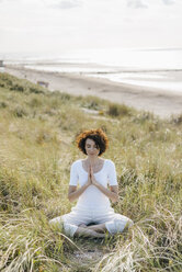 Woman practicing yoga in beach dune - KNSF02615