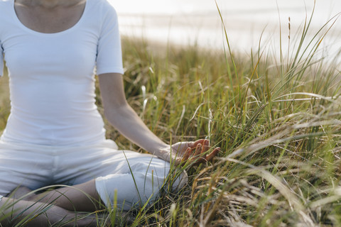 Nahaufnahme einer Frau, die in einer Stranddüne Yoga übt, lizenzfreies Stockfoto