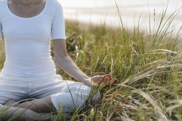 Nahaufnahme einer Frau, die in einer Stranddüne Yoga übt - KNSF02616