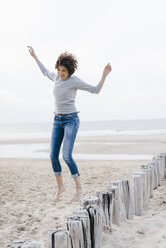 Glückliche Frau springt am Strand - KNSF02619